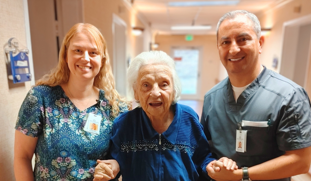 Elderly woman with her rehab team, smiling at camera